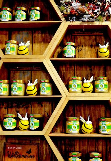 Sechseckiges Regal mit einer Auswahl an Honig aus dem Hegau. Dazwischen stehen dekorative Bienenfiguren.