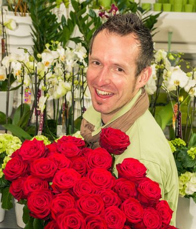 Inhaber Rainer Glöggl mit einem Bund roter Rosen
